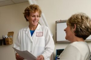 A smiling doctor in a white coat talking to a patient in a clinic