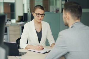 Woman in glasses interviews a man at an office desk