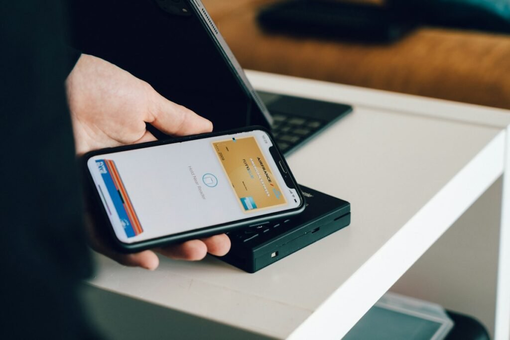 Aperson holding a smartphone over a card reader for contactless payment